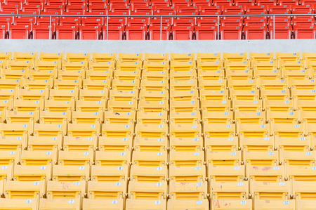 Empty orange and yellow seats at stadium,Rows of seat on a soccer stadiumの写真素材