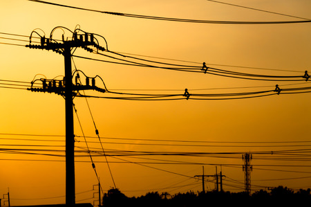 Silhouette of electric pole with cable on dramatic sunset sky, horizontal frameの写真素材