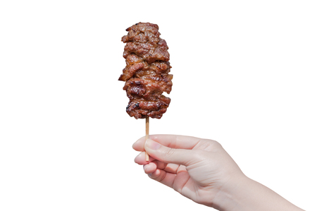 Hand holding grilled pork in bamboo stick isolate on white background,Image of grilled pork in hand , thai food styleの写真素材