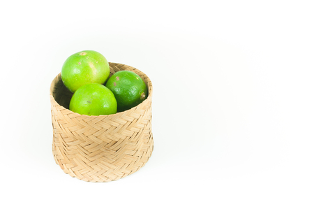 fresh green limes in the bamboo basket isolated on white background,Closeup shoot, Select focusの写真素材
