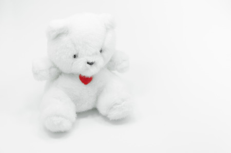 Lovely white teddy bear toy sitting with red heart on white background, fall in love teddy bear.の写真素材