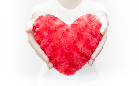 Woman holding and protecting a red heart shape on white background close-up,Symbol of love or dating Valentines dayの写真素材