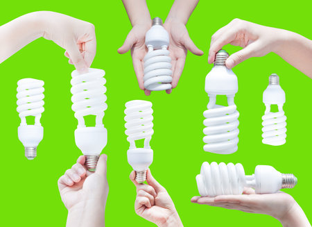 Energy saving concept. Woman hand holding light bulb on green background