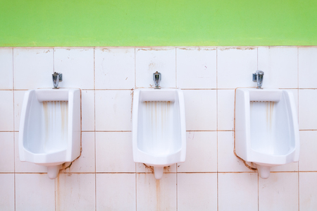 line of white porcelain urinals in public toilets, dirty toilets outdoorの写真素材