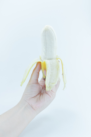 The peeled banana in a female hand holding on white background,banana fruitsの写真素材