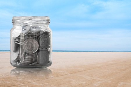 Coins in a glass jar on beach nature background ,savings coins - Investment And Interest Concept saving money conceptの写真素材