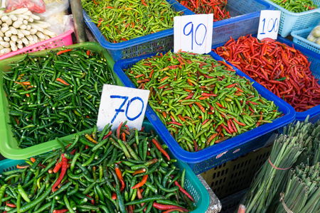 Fresh red and green hot chilies in a basket sold at local market in Thailandの写真素材