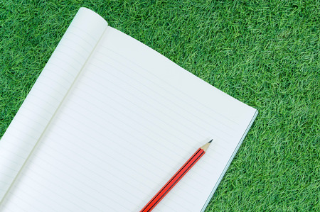 Notebook with pencil isolate on green grass background,for art education backgroundの写真素材