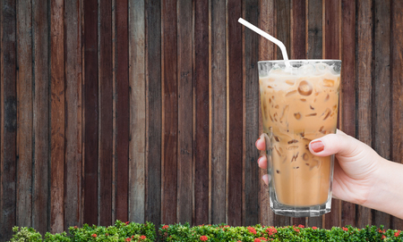 woman hand holding the glass iced coffee on wooden background,Iced latte coffeeの写真素材
