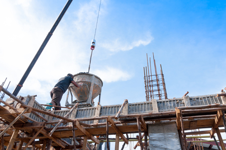 Construction building workers at construction site pouring concrete in form,Man Working at height with blue sky at construction siteの写真素材