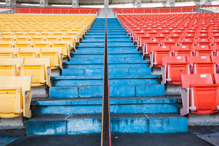 Empty orange and yellow seats at stadium,Rows walkway of seat on a soccer stadiumの写真素材