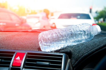 A plastic bottle of water in car for a long time.Water bottle placed on the carの写真素材