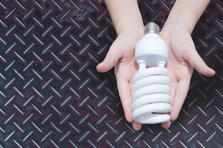 Energy saving concept, Woman hand holding light bulb on zinc iron background,Ideas light bulb in the handの写真素材