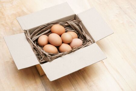 Fresh chicken eggs in paper box on the wooden tableの写真素材
