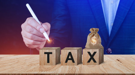 Businessman choose wooden blocks with the word Tax. Concept of reducing the tax burden. Tax avoidance. Costs and expenses of the business. Taxation. Pay off debt. Freedom from illegal taxesの写真素材