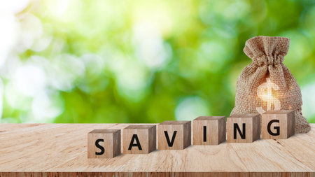 Wooden blocks with words saving and US dollar money bag for investment loan planned future concept. saving, charity, family finance plan concept, fundraising, superannuation, financial crisis conceptの写真素材