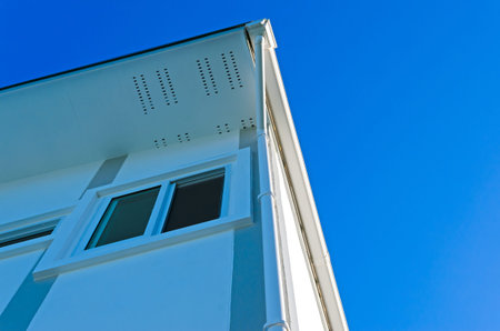 House roof with rain gutter of roof top house and large windows on blue sky background, New modern...