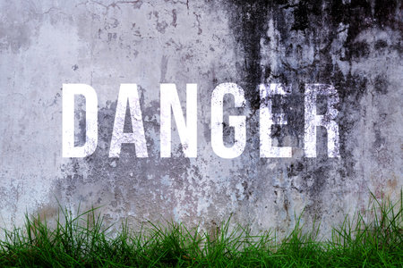 Danger text written with broken cement wall, Danger word on street.の写真素材