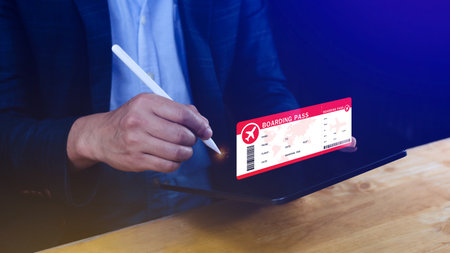 Hand holding boarding pass tickets air travel concept, Choosing checking electronic flight ticket on laptop.の写真素材