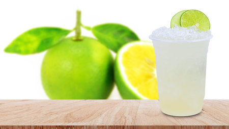 Cool freshly made lemonade in a plastic cups with crushed ice and lemon slices on wooden table with...