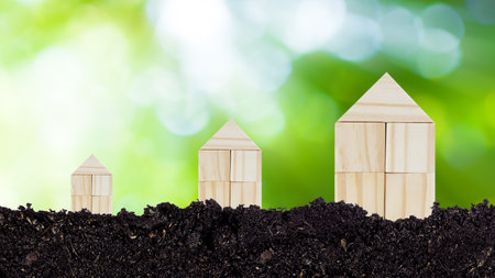 Closed up tiny toy wooden house model on ground with sunlight bokeh background, concept of growth, real estate, investments for the purchase of real estate. Home concept.の写真素材