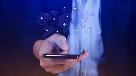 Businessman hand pushing flight booking networking with smart phone, Hand pressing light blue world map with flight routes airplane on blue background, Transportation concept.の写真素材