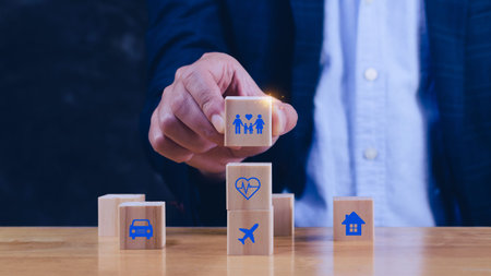 Businessman hand choose wooden blocks with icons of various types of insurance, protection icons for safety family insurance. Life insurance concept.の写真素材