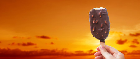 Chocolate covered ice cream bar with silhouetted sunset summer at the beach, during the holidays....