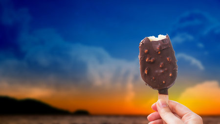 Chocolate covered ice cream bar with silhouetted sunset summer at the beach, during the holidays....