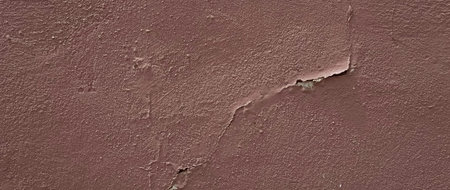 Weathered and peeling paint on wall. dark brown paint peeling on wall. old concrete wall has cracks...