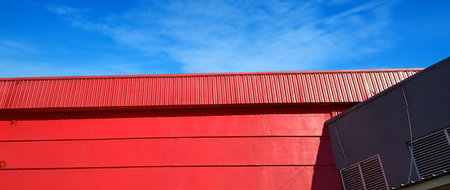 Red Metal sheet roof curve on blue sky. Modern construction, Metal ribbed arch span roof covering, Large building  roof. not aiの写真素材