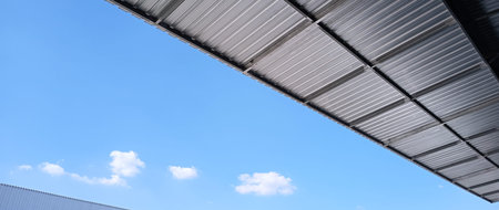 Metal sheet roof curve on blue sky. Modern construction, Metal ribbed arch span roof covering, Large...