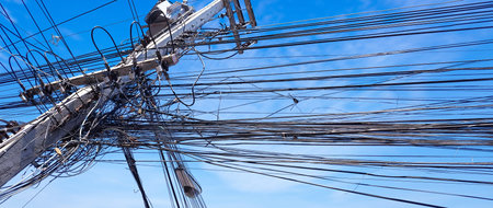 Tangled and messy electrical power cables and wires on utility pole, symbolizing chaotic...