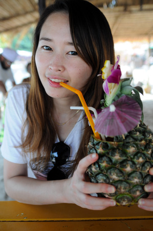 Young asian female drinking pineapple juiceの写真素材