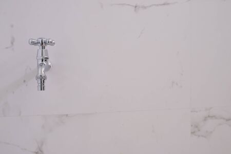 Silver water valve on the white wall in bathroomの写真素材