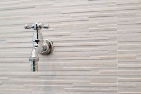 Silver water valve on the white wall in bathroomの写真素材
