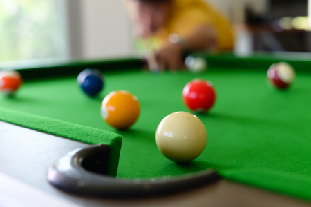 Young man playing pool in a bar.focus on the ballの写真素材