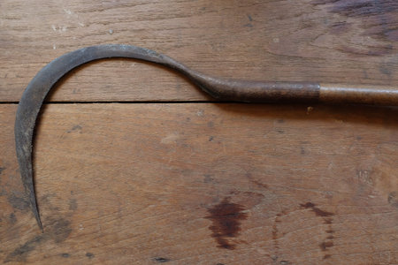 Sickle on wooden background.