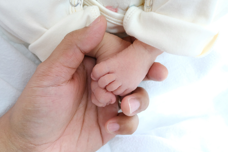 Parent holding in the hands feet of newborn baby.の写真素材