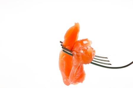 a piece of salted trout on a fork over white backgroundの写真素材