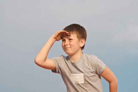 the boy looks into the distance against a cloudless skyの写真素材
