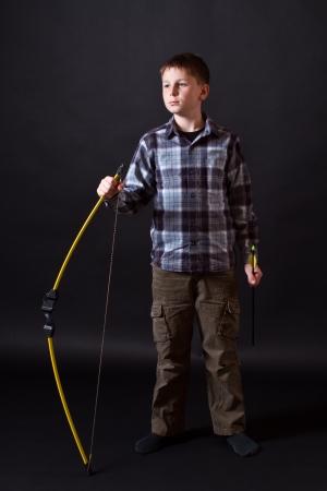 boy shoots a bow on a black backgroundの写真素材