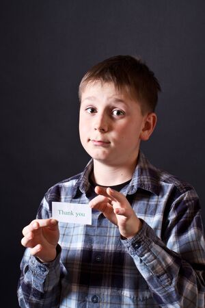 boy shows a card with gratitude on a black backgroundの写真素材