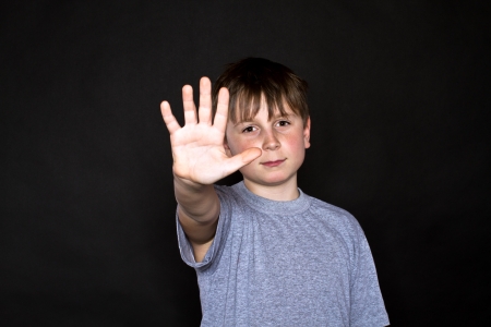 boy shows his hand to stop on a black backgroundの写真素材
