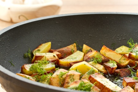 potatoes fried in oil in a frying pan with dillの写真素材
