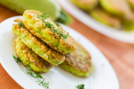 fried zucchini fritters with dill on a plateの写真素材
