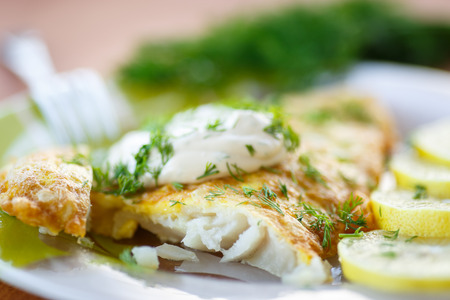 fried fish with sauce and lemon on a plateの写真素材