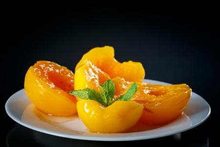 canned peach halves on a black backgroundの写真素材