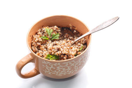 Boiled buckwheat with butter in a cup on a white backgroundの写真素材