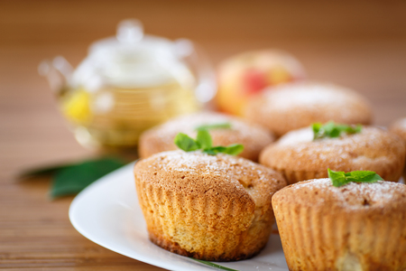 sweet apple muffins with tea on wooden tableの写真素材
